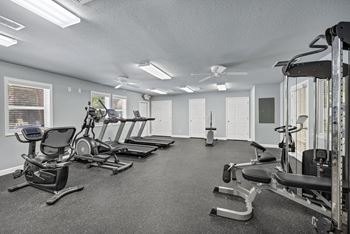 A spacious gym with a variety of equipment including treadmills, stationary bikes, and weight machines.